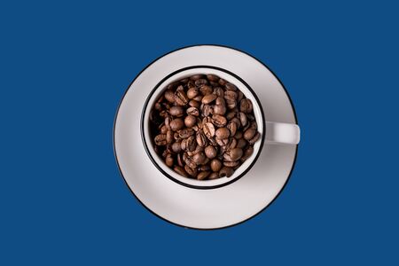 Cup with coffee beans isolated on trendy classic blue background, copy space for text.の写真素材