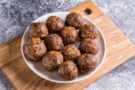 Energy balls with dried fruits and nuts in a plate on gray concrete background. Healthy vegan food...