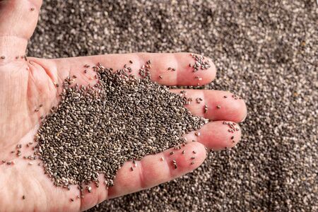 Chia seeds in a woman's hand over yellow Cuscus background.の写真素材