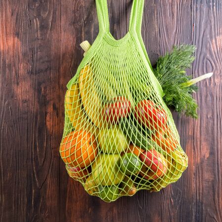 Fresh fruits in string shopping bag on wooden table.の写真素材