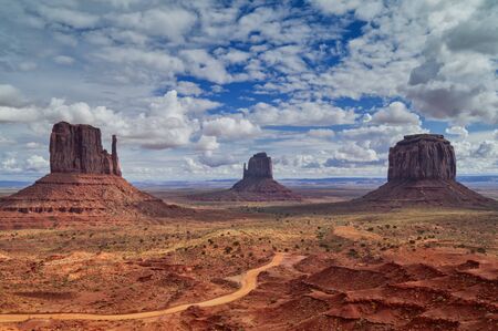 Travel through the national parks of the southwestern United States: a view on the rock formations of monument Valley in Utah. Uneven dirt road.の写真素材