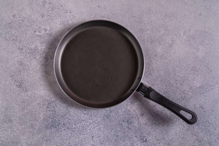Empty black pan on gray table top view, copy space for text.