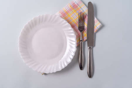 An empty white plate and Cutlery on top of a napkin, space for text, top view.の写真素材