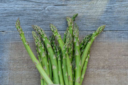 Bunch of fresh green asparagus spears on a rustic wooden table summer outdoor, flat lay.の写真素材
