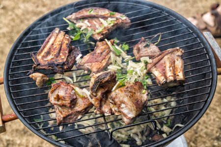 Cooking lamb ribs on round grill. The concept of a picnic in the fresh air.