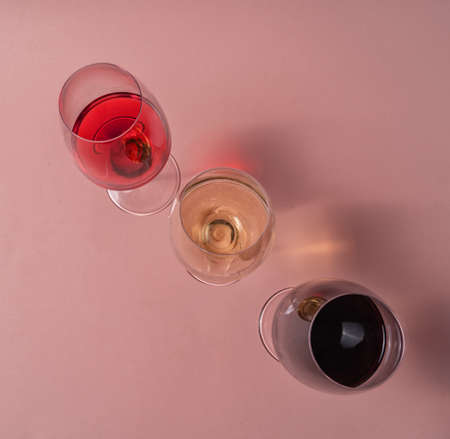 Glasses of red, rose and white wine on pink background, flat lay, top view.の写真素材