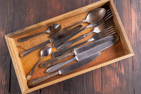 Cutlery in a wooden box. on wood table. The view from the top.