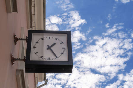 Modern street clock on the wall of a building.