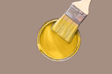 A can of yellow paint and a large one on a brown background. Copy the space for your text.の写真素材