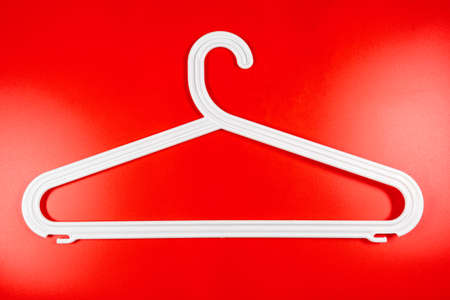 Plastic white coat hanger clothes hanger on a red background.の写真素材
