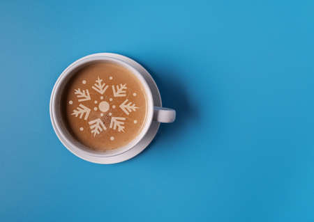 A Cup of coffee with milk in a blue mug on a blue background, and the silhouette of a Christmas tree on the foam, flat lay, copy space. Christmas concept.の写真素材