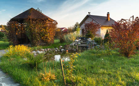 landscape with Garden pond and small country cabin in countryside. Rural scene.