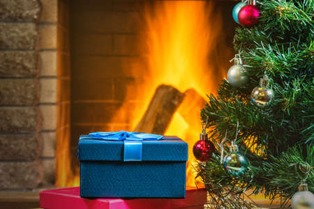 Christmas eve. New year tree and Gift boxes near cozy fireplace, in country house.の写真素材