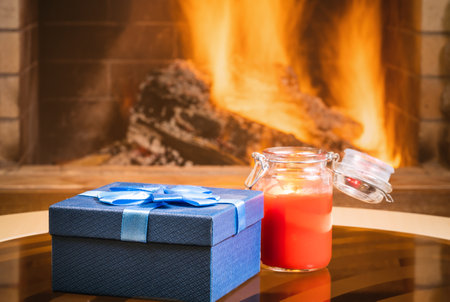 Christmas Gift box and candle near cozy fireplace, in country house.の写真素材