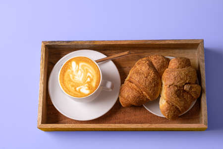 Latte art coffee, croissants on trendy Very Peri color - color of the year 2022 background.