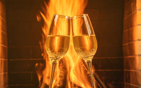 Two glasses of champagne in front of a cozy burning fireplace in a country house.の写真素材
