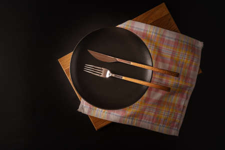 Cutlery on a black plate, isolated on a black background, top view, flat lat.の写真素材