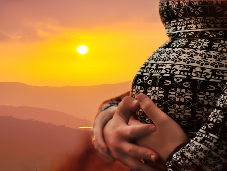 Pregnant women wraps her arms around belly in the form of the heart.の写真素材