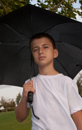 Boy looking at camera while under umbrella outside  .の写真素材
