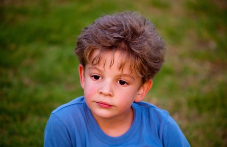 Portrait of happy joyful beautiful little boy  against the background of grass .の写真素材