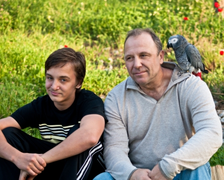 Portrait of a boy teenager and his father with a gray parrot Jaco.の写真素材