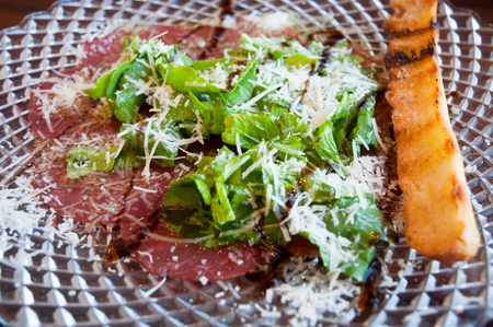 Carpaccio- fresh sliced raw beef with lettuce with parmesan cheese on the transparent plate.の写真素材