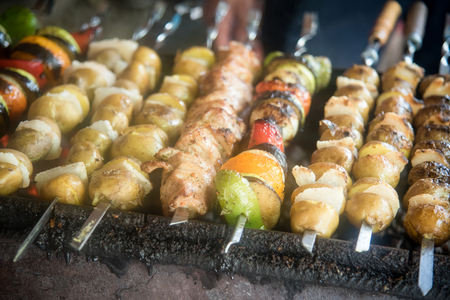 Fried potatoes with lard and bacon on skewers , skewers of meat and mixed colorful vegetables .の写真素材