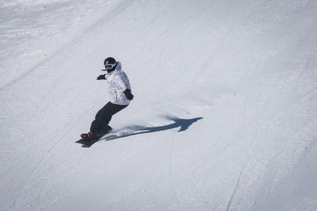 Young man a snowboarder  descends a backcountry at  from a slope .