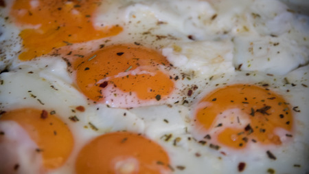 Fresh fried eggs served with spices closeup.