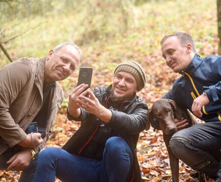 Men in the autumn forest make selfie with the dog.の写真素材