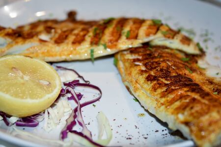 Fresh fried fillet of sea bass. Grilled Mediterranean fish, served with herbs and lemon.の写真素材