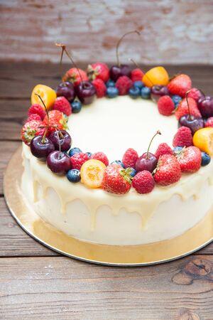 Cheesecake with white chocolate, fresh berries, strawberries, cherries, blueberries and raspberries on wooden background. Summer dessert.の写真素材