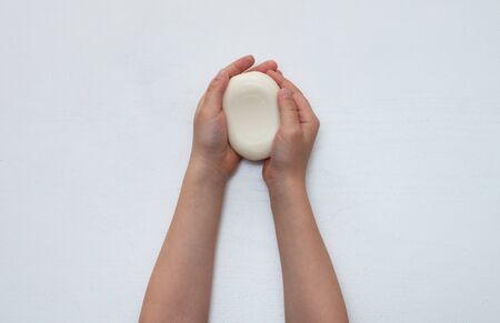 Child hands holding white soap bar. Plain white background. Isolated. Healthy lifestyle concept.の写真素材