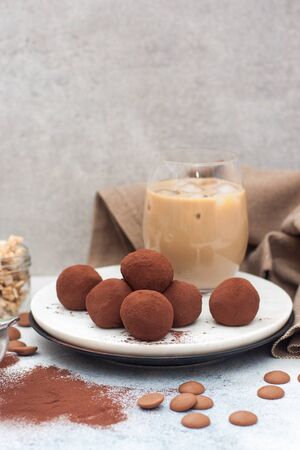 Cold coffee liqueur with chocolate truffles, rolled in cocoa powder on grey background