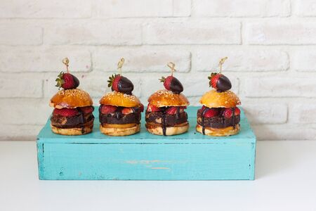 Sweet burgers with brioche bun, chocolate brownie layer, fresh strawberries and melted chocolate...