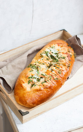 Garlic bread with cheese and herbs on wooden box, light grey background