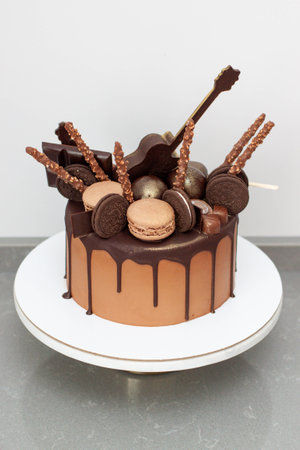 Delicious chocolate cake with melted chocolate, candies, guitars, popsicles, macarons and nameplate...
