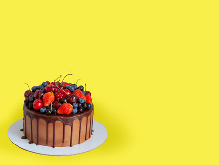 Chocolate cake with fresh berries, strawberry, cherry, blueberry isolated on yellow background. horizontal orientationの写真素材
