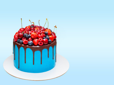 Beautiful blue birthday cake decorated with fresh berries with a place for a label. The concept of summer desserts for a birthdayの写真素材