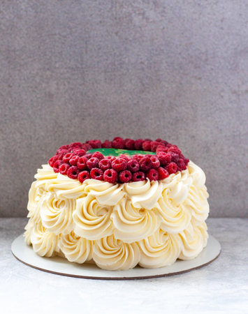 Cake with cream roses and raspberries on plain gray background, copy spaceの写真素材