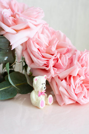 Cute edible teddy bear toy made of white chocolate with fresh peonies and candles on the backgrounds. Gift for a babyの写真素材