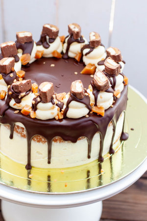 Twix inspired cake with melted chocolate, cookies, salted caramel and sweet bar