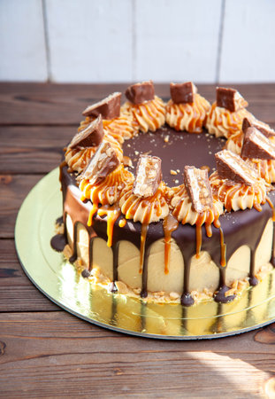 Gorgeous snickers cake with peanut butter cream, melted chocolate, candy bars and salted caramelの写真素材