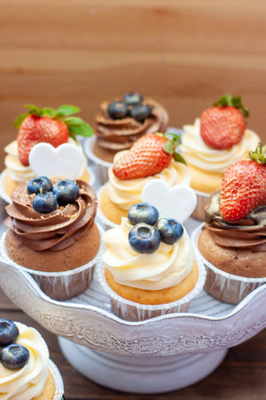 Chocolate and vanilla cupcakes with blueberries and fresh strawberry on a marble cake standの写真素材