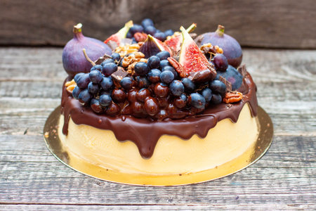 Delicious vanilla cheesecake poured with melted dark chocolate, figs, grape, pecan nuts on the top. Harvest autumn decorationの写真素材