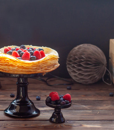 Stack of traditional crepes on wooden b;ack background with fresh berries on the top. Maslenitsa traditional Russian festival meal.の写真素材