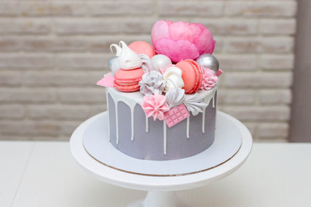 Beautiful and elegant gray cake decorated with melted white chocolate, macaroons, pink peony flower...