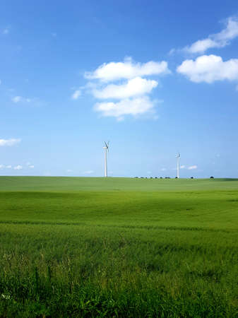 Wind turbine on the background of green meadows and blue sky.の写真素材