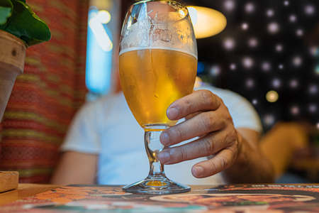 The man's hand puts down the glass and pours the beer over blurred background.の写真素材