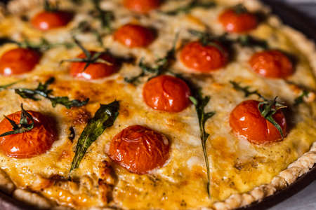 Quiche Lorraine with custard, close-up, soft focus. Open French pie with cream filling Quiche Lorraine. Baked tomatoes on the surface of the pie, crispy crust of shortcrust pastry, appetizing pieの写真素材